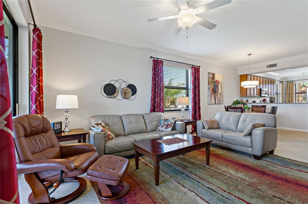 A living room features light gray leather sofas, a brown leather recliner, and patterned curtains — 7015 RIVER HAMMOCK DRIVE UNIT 208, BRADENTON, FL