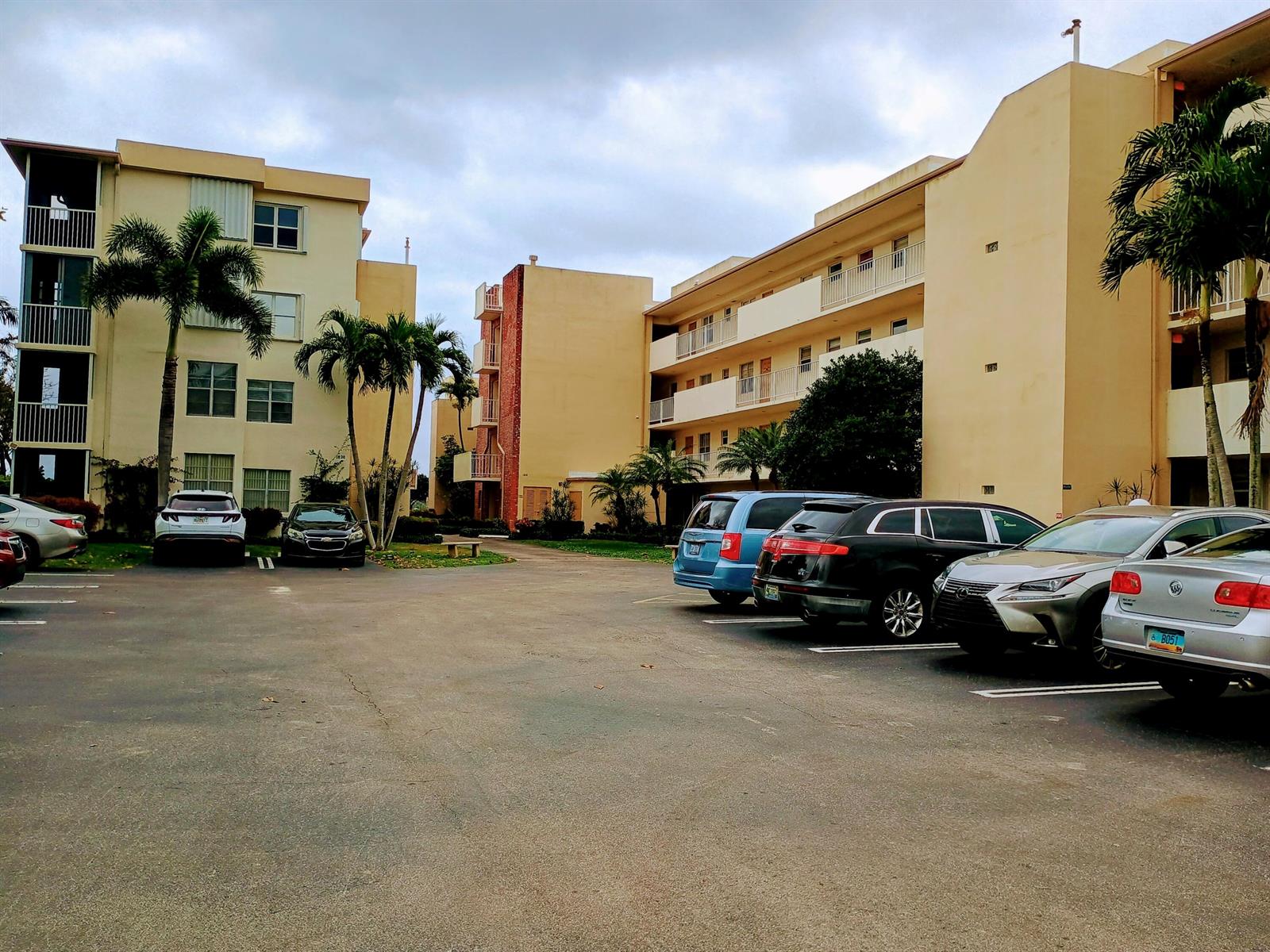 A parking lot sits in front of two multi-story apartment buildings with palm trees — 1810 New Palm Way # 215, Boynton Beach FL 33435, BOYNTON BEACH, FL
