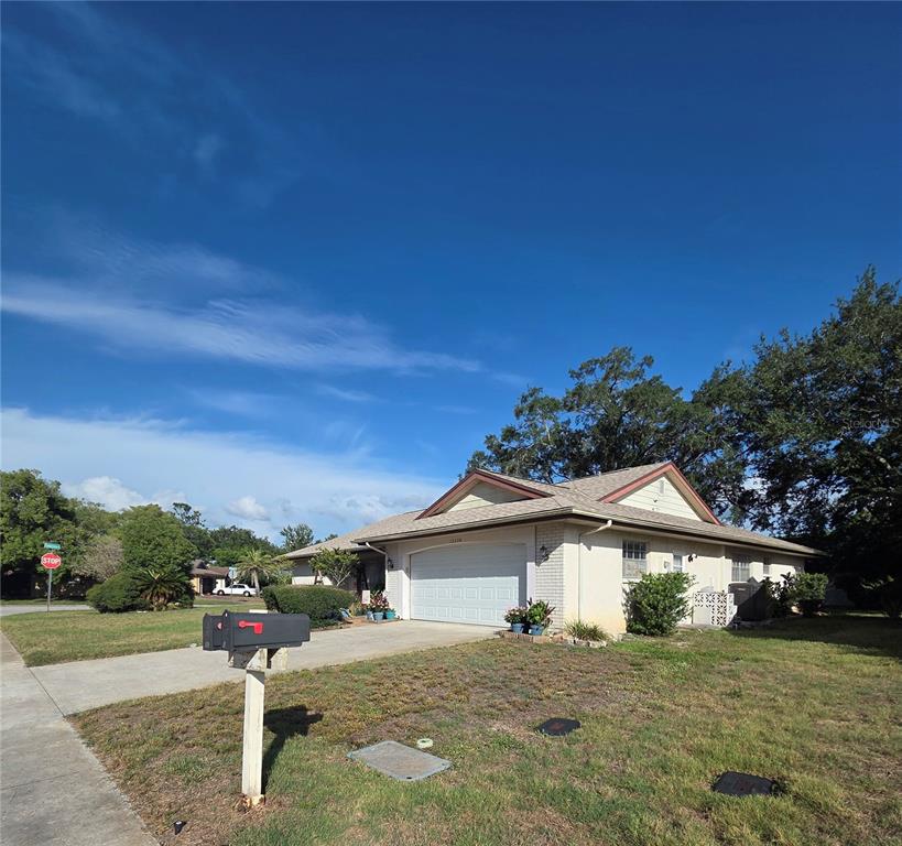 A single-story house with a white garage door and a beige brick exterior — 12226 MEADOWBROOK LANE, HUDSON, FL