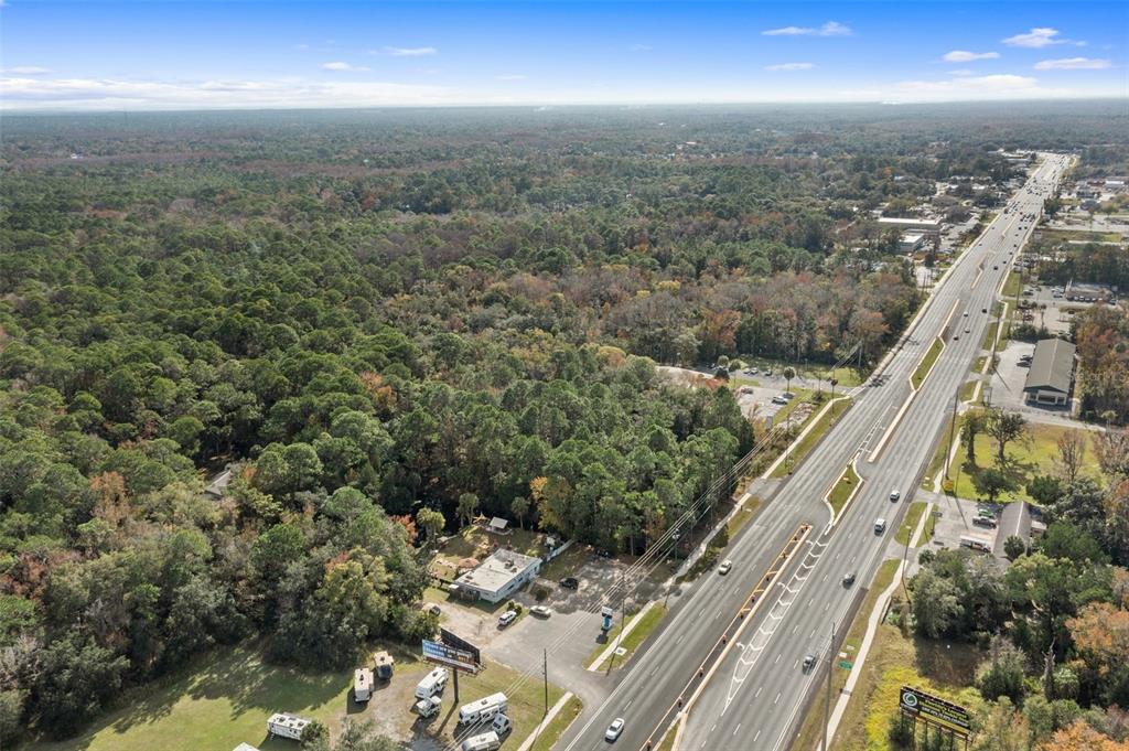 An aerial view shows a commercial property along a multi-lane highway bordered by dense forest — 3409 S SUNCOAST BOULEVARD, HOMOSASSA, FL