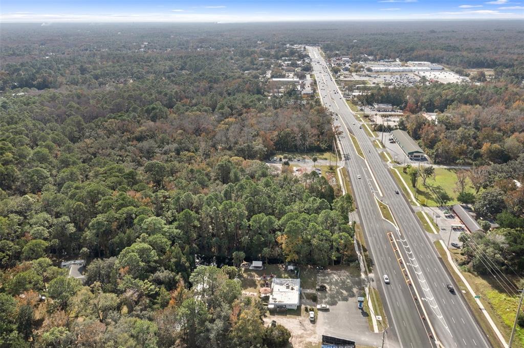 An aerial view shows a commercial property adjacent to a multi-lane highway and dense forest — 3409 S SUNCOAST BOULEVARD, HOMOSASSA, FL
