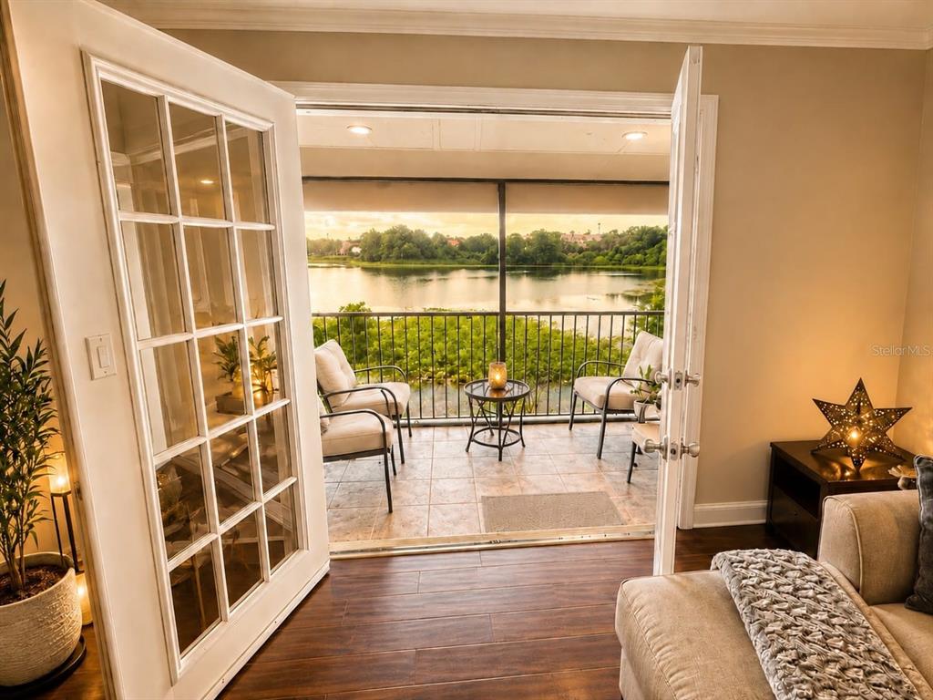 French doors open from a living room to a balcony overlooking a lake — 145 N PEARL LAKE CAUSEWAY UNIT 210, ALTAMONTE SPRINGS, FL