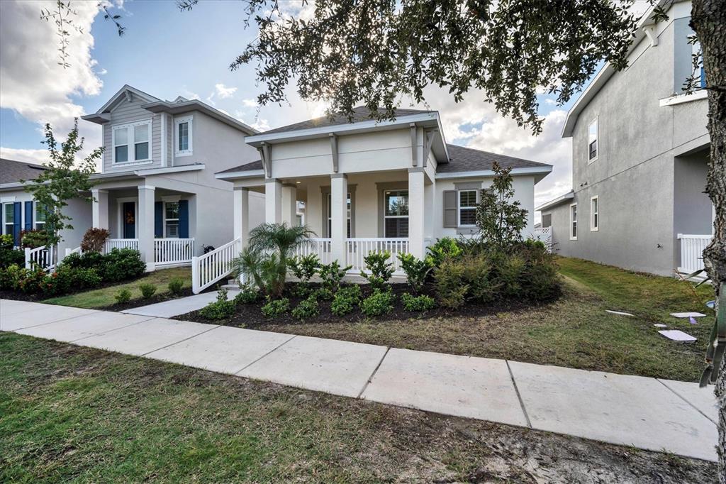 A single-story house with a white porch and landscaping sits behind a concrete sidewalk — 724 WINTERSIDE DRIVE, APOLLO BEACH, FL