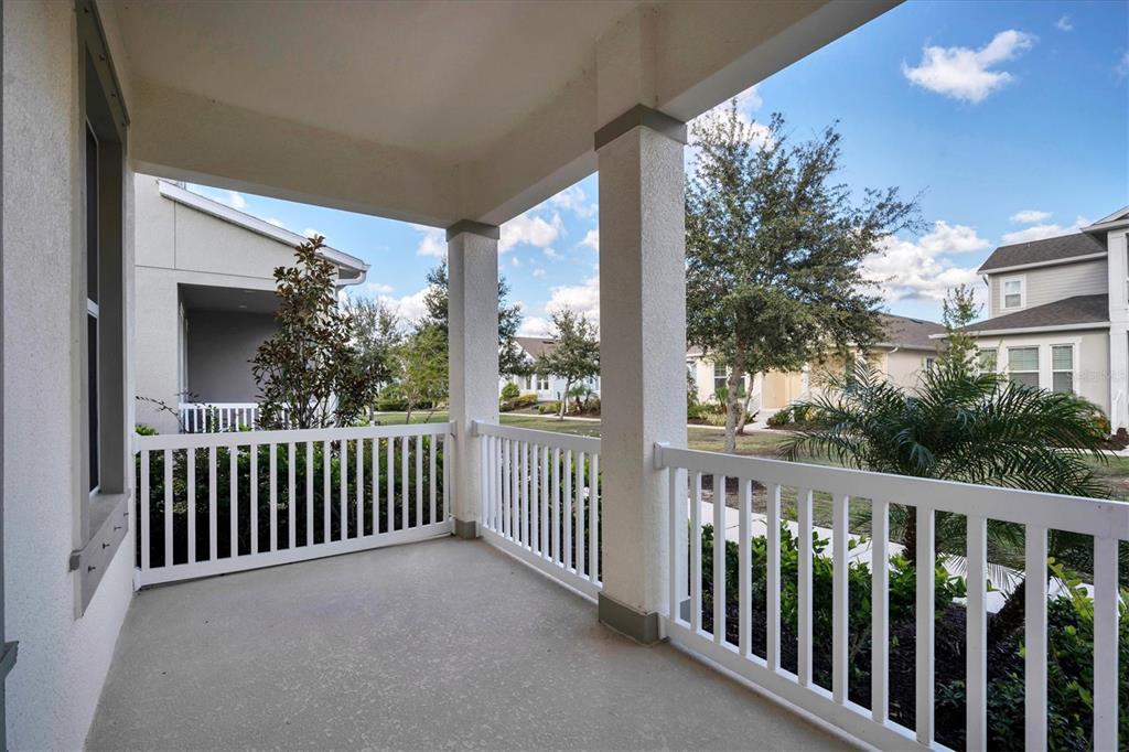 A covered porch features white railings, concrete flooring, and views of neighboring houses and trees — 724 WINTERSIDE DRIVE, APOLLO BEACH, FL