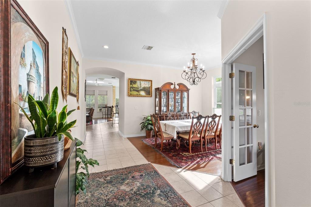 A dining room with a chandelier and hutch sits off a tiled entryway and hallway — 8434 WESTERLAND DRIVE, LAND O LAKES, FL
