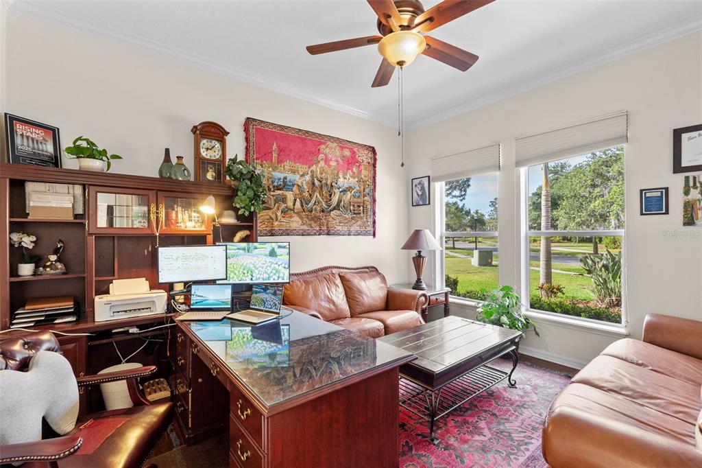 A home office features a large wooden desk, leather sofas, and a tapestry on the wall — 8434 WESTERLAND DRIVE, LAND O LAKES, FL