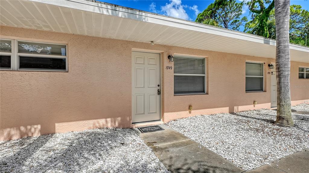 A peach-colored exterior wall features a white front door and windows with horizontal blinds — 1749 HILLVIEW STREET UNIT 1, SARASOTA, FL