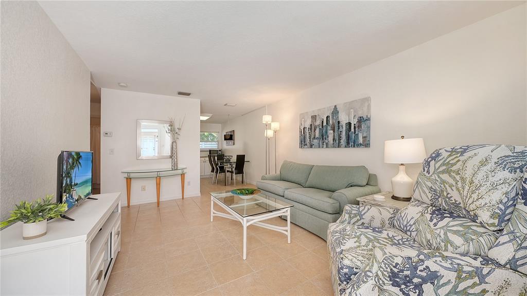 A living room with tile floors, a light green sofa, and a patterned armchair — 1749 HILLVIEW STREET UNIT 1, SARASOTA, FL