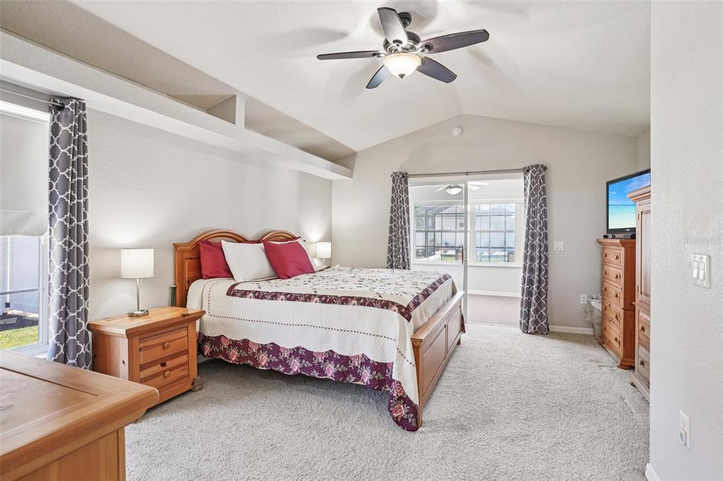 A bedroom features a wooden bed frame, a ceiling fan, and sliding glass doors — 5353 COUNTY ROAD 125, WILDWOOD, FL
