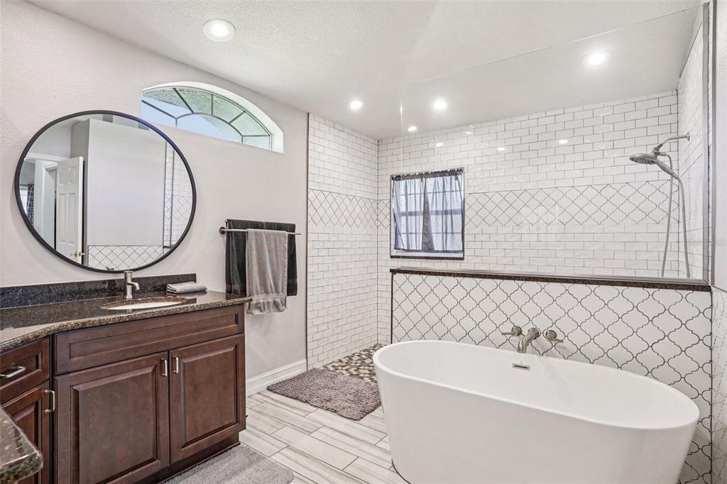A bathroom features a dark wood vanity, a freestanding tub, and a tiled walk-in shower — 5353 COUNTY ROAD 125, WILDWOOD, FL