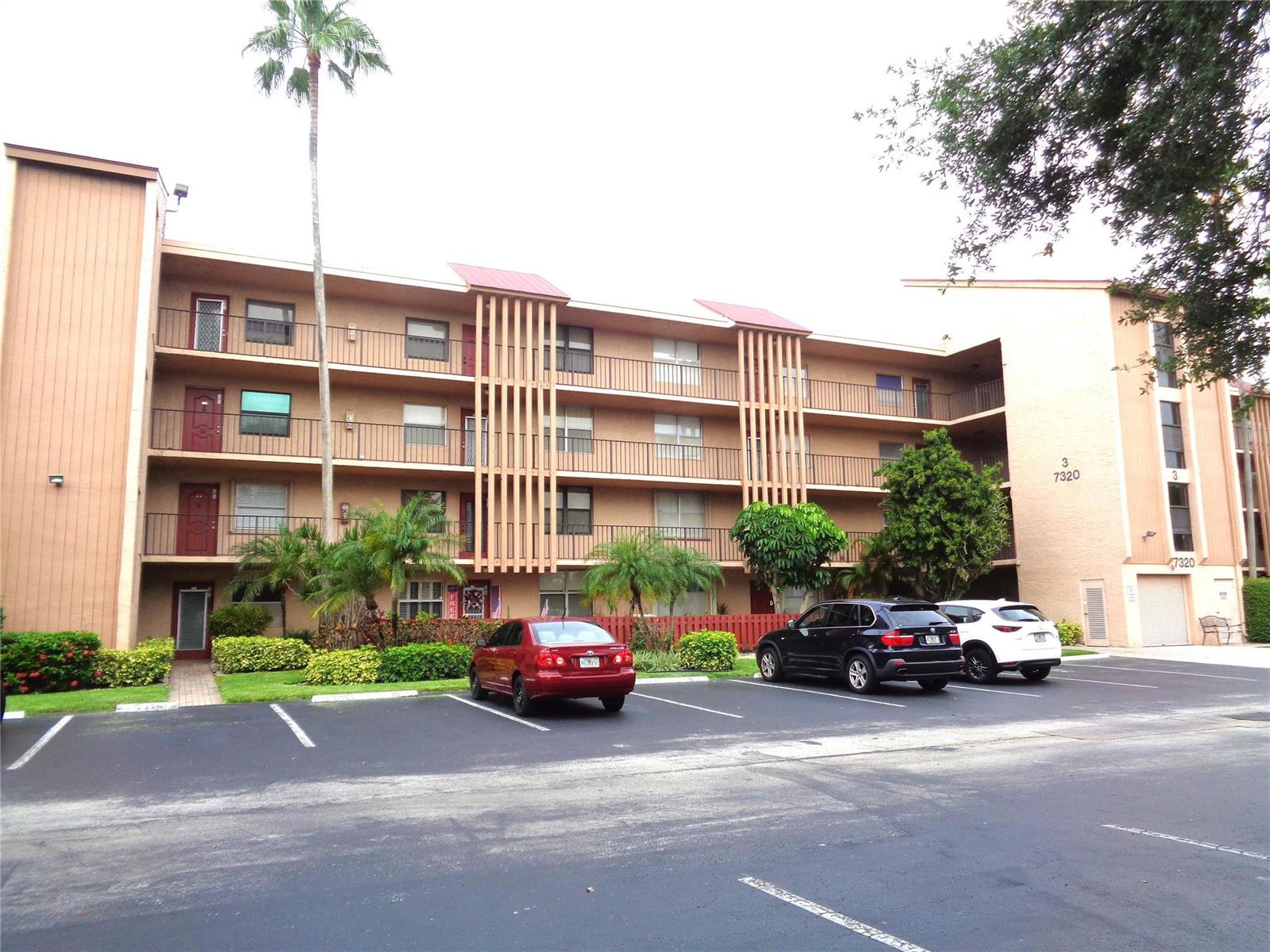 A three-story apartment building with a parking lot in front and palm trees — 7320 Lake Circle Drive # 101, Margate FL 33063, MARGATE, FL