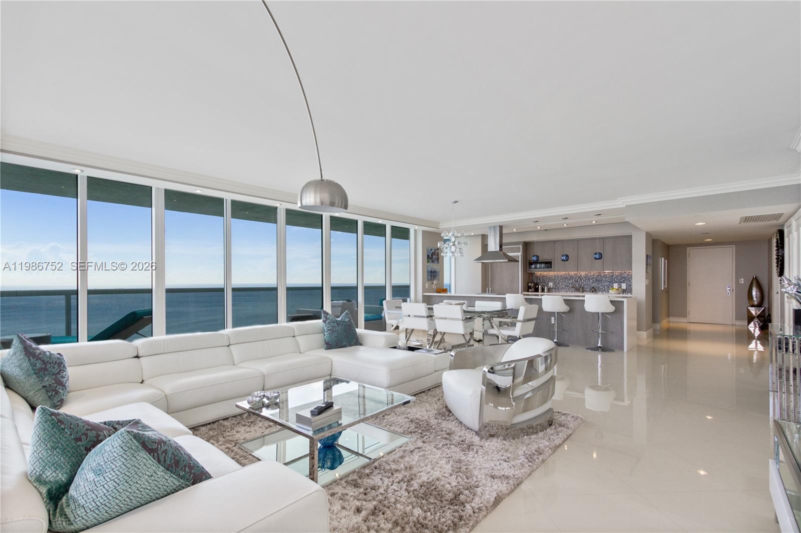 A modern open-concept living room features a white sectional, glass coffee table, and ocean views — 1830 S Ocean Dr # 3401, Hallandale Beach FL 33009, HALLANDALE BEACH, FL
