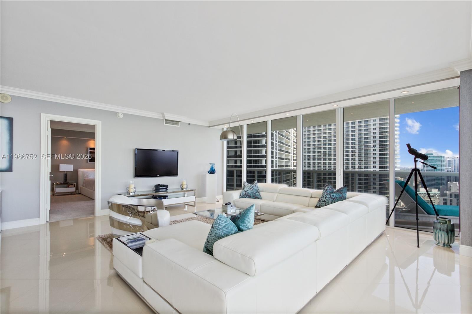A modern living room features a large white sectional sofa, tile floors, and floor-to-ceiling windows — 1830 S Ocean Dr # 3401, Hallandale Beach FL 33009, HALLANDALE BEACH, FL