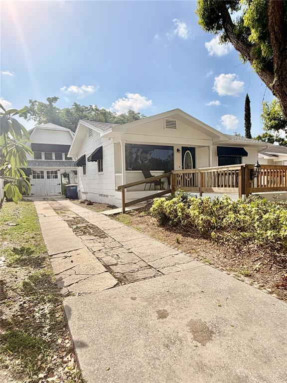 A white house with a wooden porch and a stone driveway sits under a blue sky — 1249 SEDEEVA CIRCLE S, CLEARWATER, FL