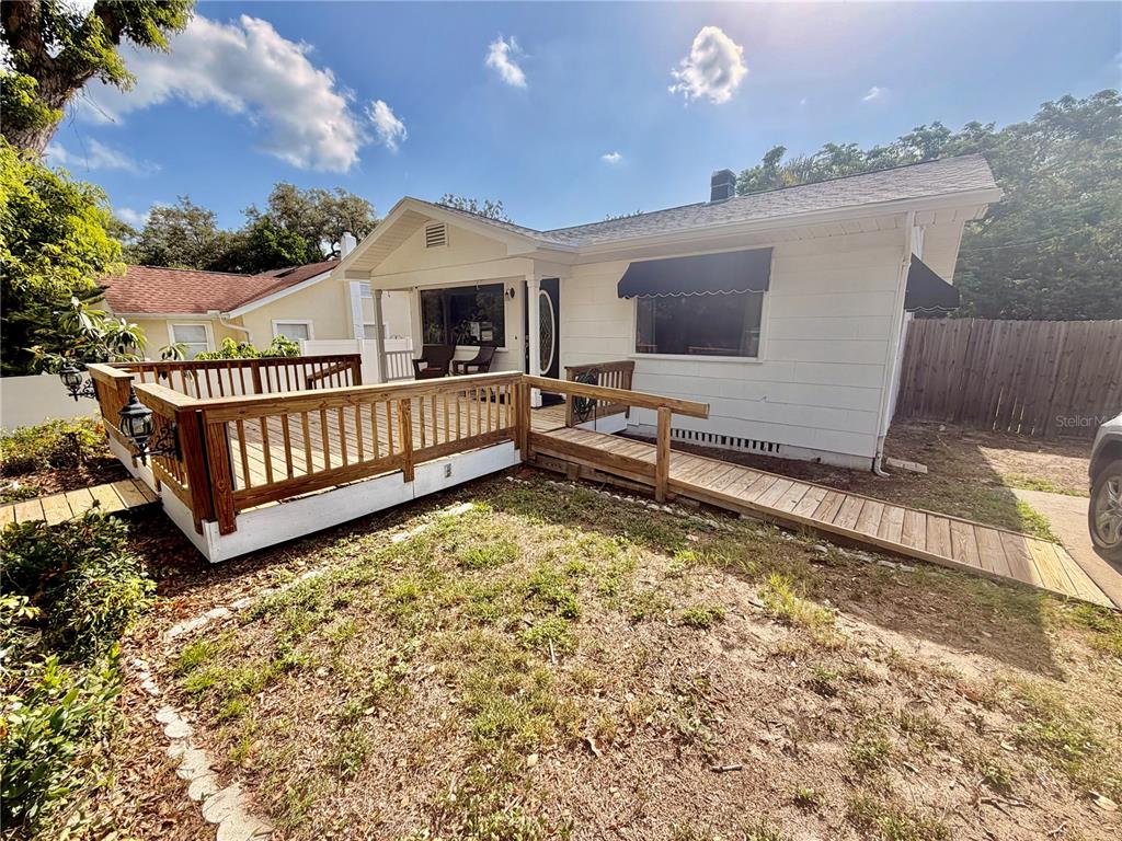 A white house features a wooden deck and an accessible ramp in the front yard — 1249 SEDEEVA CIRCLE S, CLEARWATER, FL