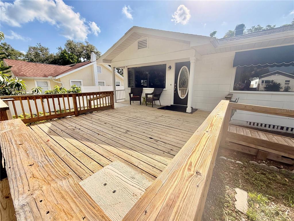 A wooden deck leads to the front entrance of a white house with a porch — 1249 SEDEEVA CIRCLE S, CLEARWATER, FL