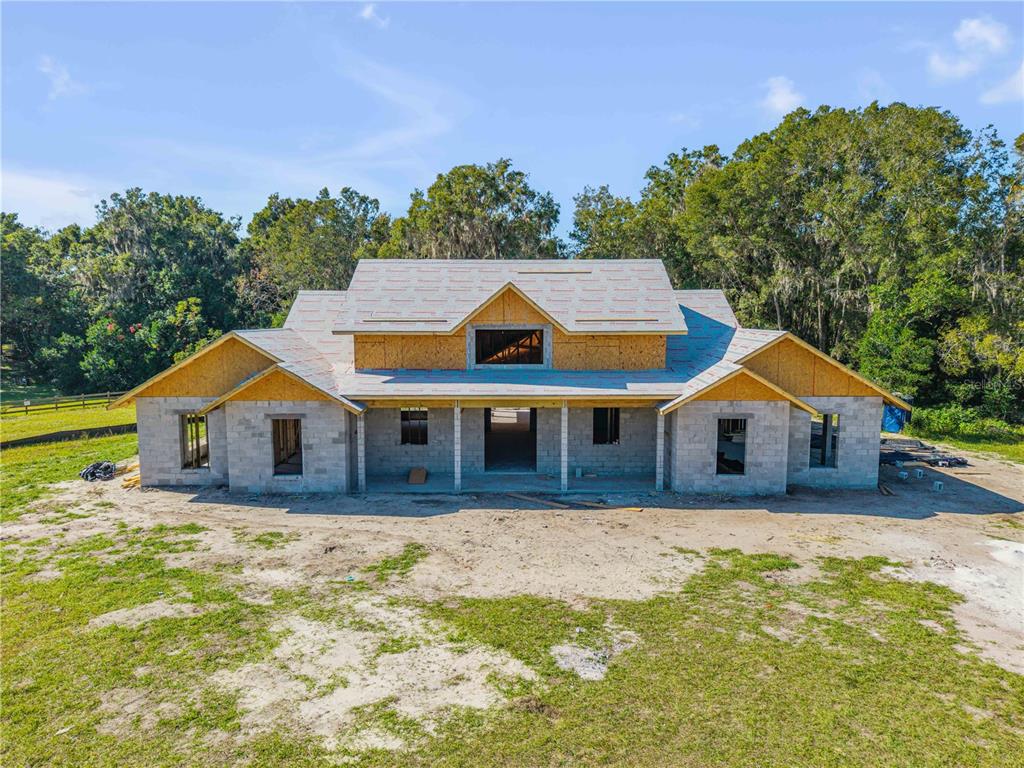 A white farmhouse with a metal roof sits on a large, grassy lot — 1624 GREENS DAIRY ROAD, DELAND, FL