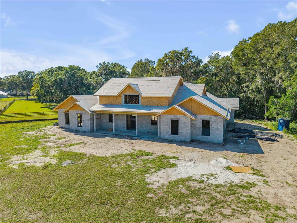 A white farmhouse-style house with a metal roof sits on a large, grassy lot — 1624 GREENS DAIRY ROAD, DELAND, FL