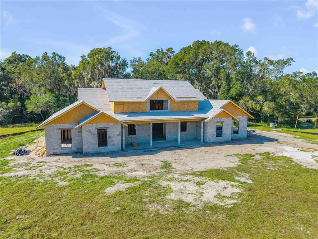A gravel driveway leads to a white garage with a metal roof beside a field — 1624 GREENS DAIRY ROAD, DELAND, FL