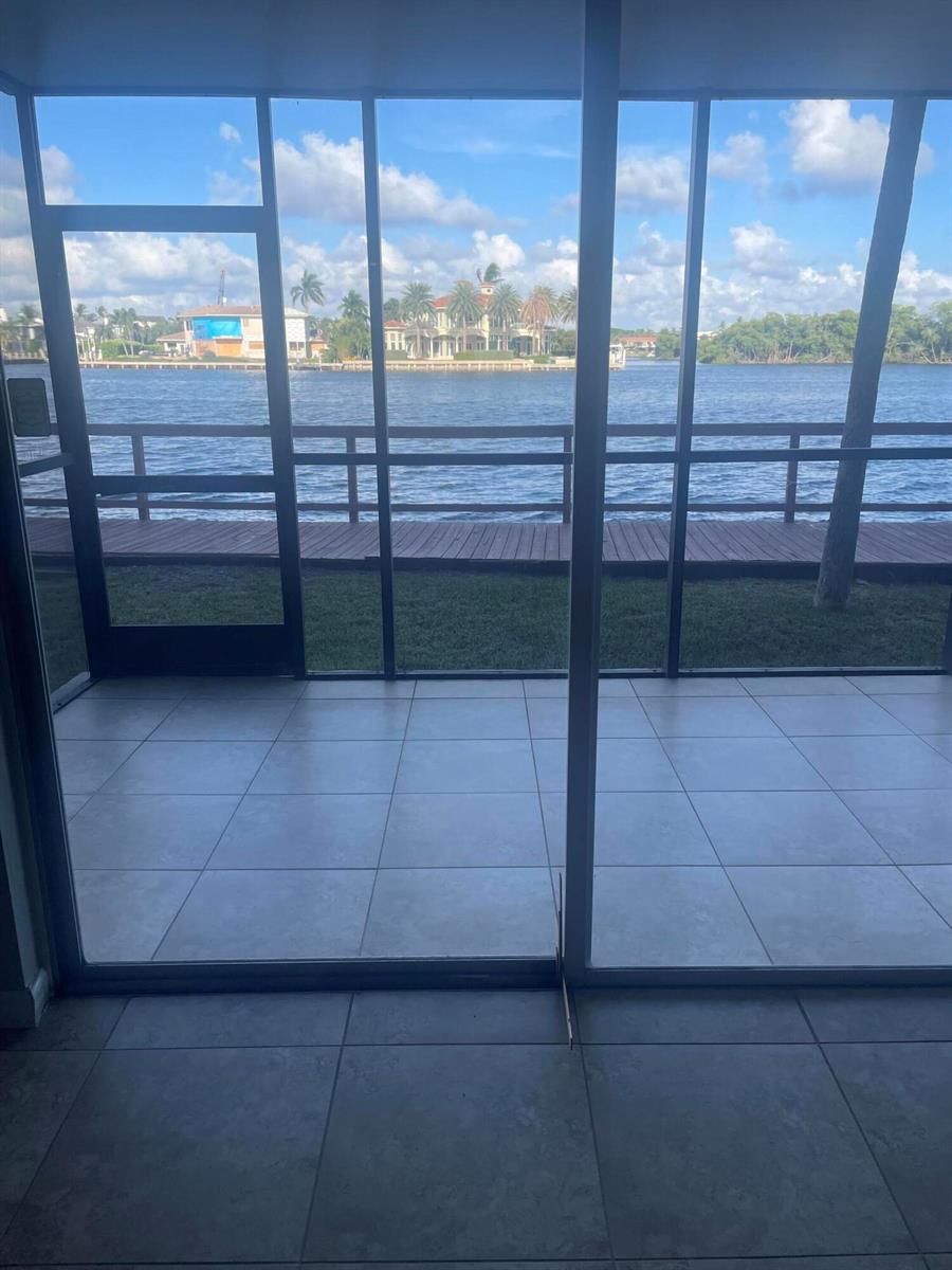 A tiled patio with a screen enclosure overlooks a waterfront view with a wooden dock — 710 NE 7th Street # 303, Boynton Beach FL 33435, BOYNTON BEACH, FL