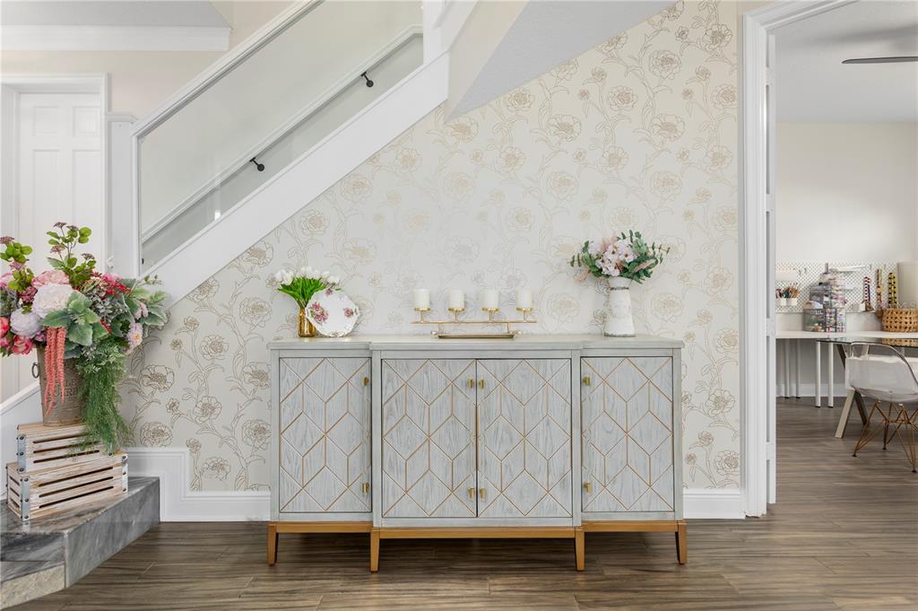 A gray sideboard with gold geometric detailing sits against a floral wallpapered wall under stairs — 8455 FOXWORTH CIRCLE UNIT 3, ORLANDO, FL