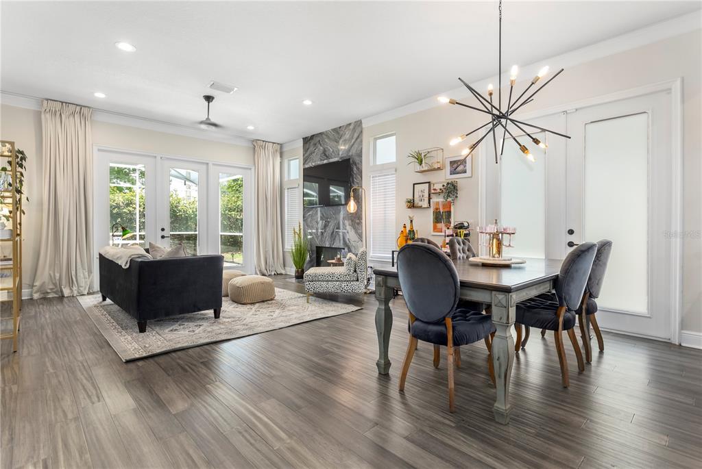 An open-concept living and dining area features wood-look flooring, a marble fireplace, and a chandelier — 8455 FOXWORTH CIRCLE UNIT 3, ORLANDO, FL
