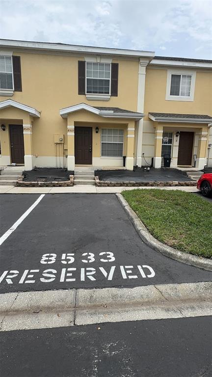 An exterior view of a multi-unit townhouse complex with reserved parking spaces in the foreground — 8533 TRAIL WIND DRIVE, TAMPA, FL