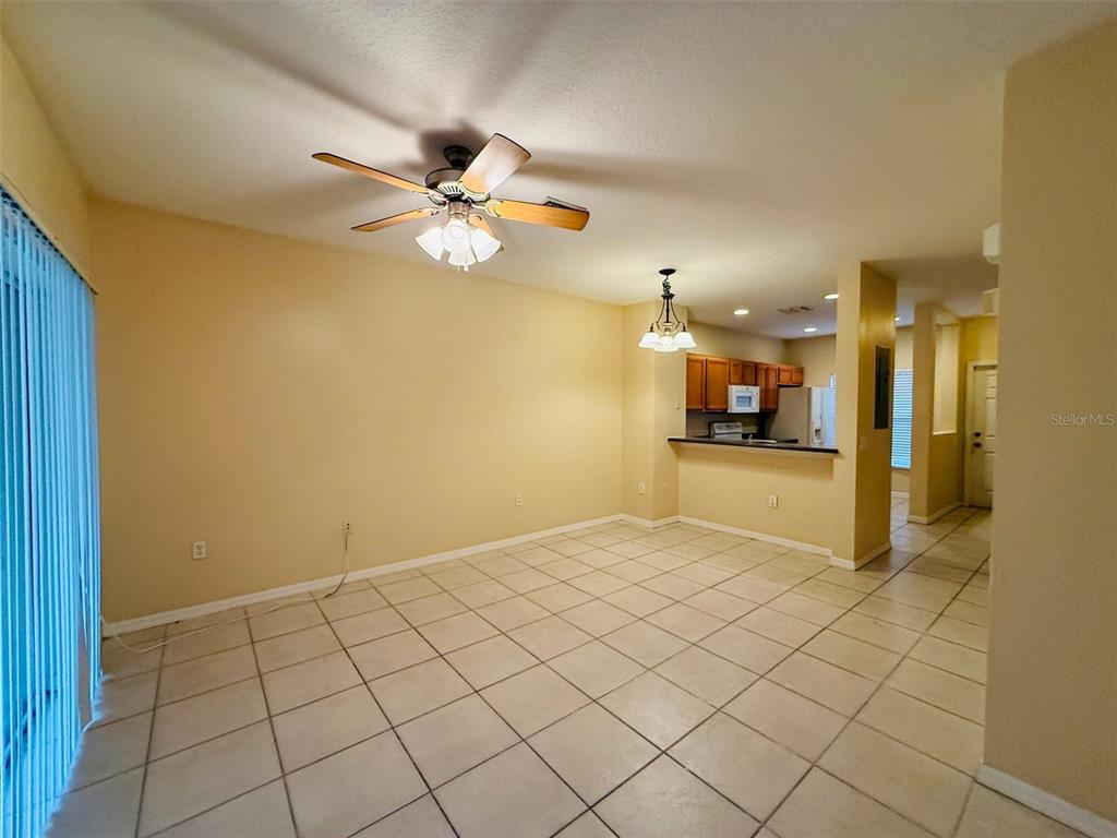 An open-concept living and dining area features light-colored tile flooring and a ceiling fan — 8533 TRAIL WIND DRIVE, TAMPA, FL