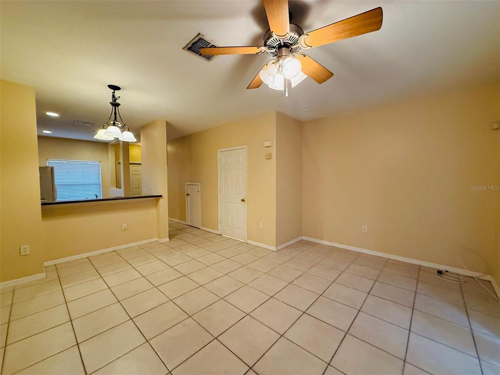 An open-concept room features light-colored tile flooring, beige walls, a ceiling fan, and a breakfast bar — 8533 TRAIL WIND DRIVE, TAMPA, FL