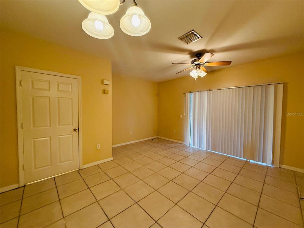 A dining area with beige walls, tile flooring, a ceiling fan, and sliding glass doors — 8533 TRAIL WIND DRIVE, TAMPA, FL