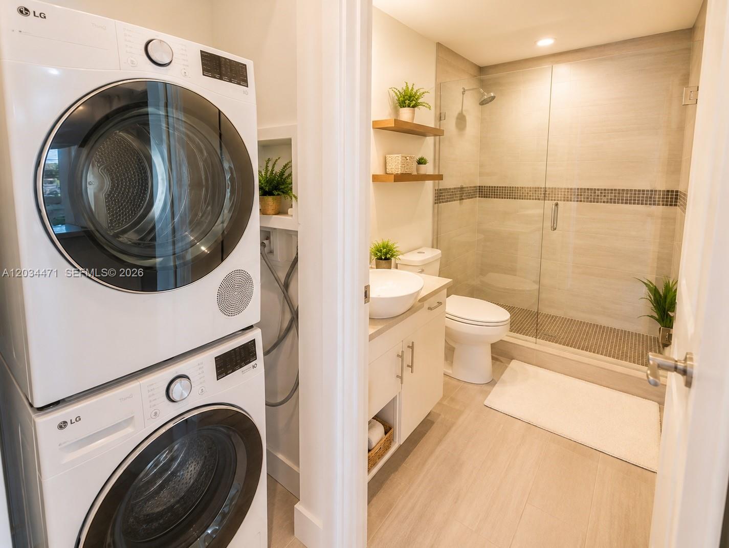 A stacked washer and dryer unit sits beside a bathroom with a glass-enclosed shower — MIAMI BEACH, FL