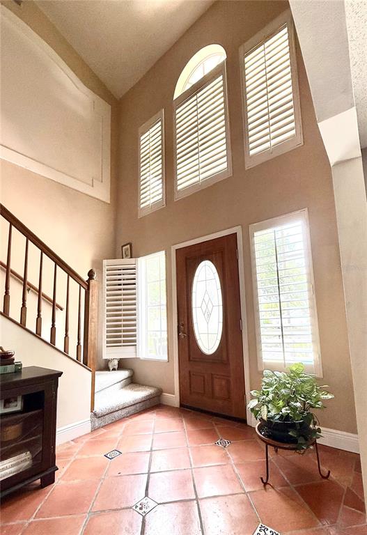 An entryway features a wooden front door, a staircase, and tall windows with plantation shutters — 1701 BRIDLEWALK COURT, GOTHA, FL