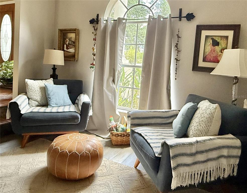 A living room features two dark armchairs, a leather pouf, and an arched window — 1701 BRIDLEWALK COURT, GOTHA, FL