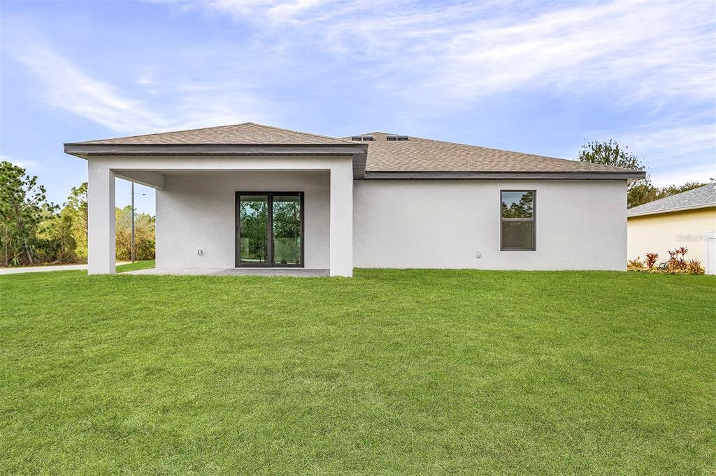 The rear exterior of a single-story house features a covered patio and a grassy yard — 4562 TAHITI STREET, NORTH PORT, FL