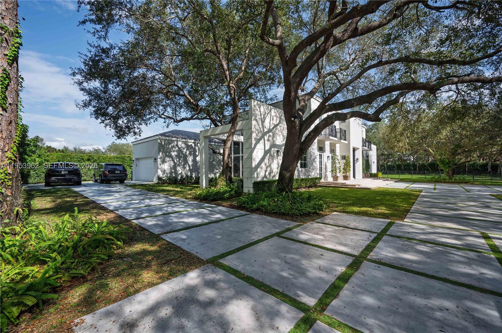 A modern white house features a large tree and a concrete paver driveway — 6355 SW 114th St, Pinecrest FL 33156, PINECREST, FL