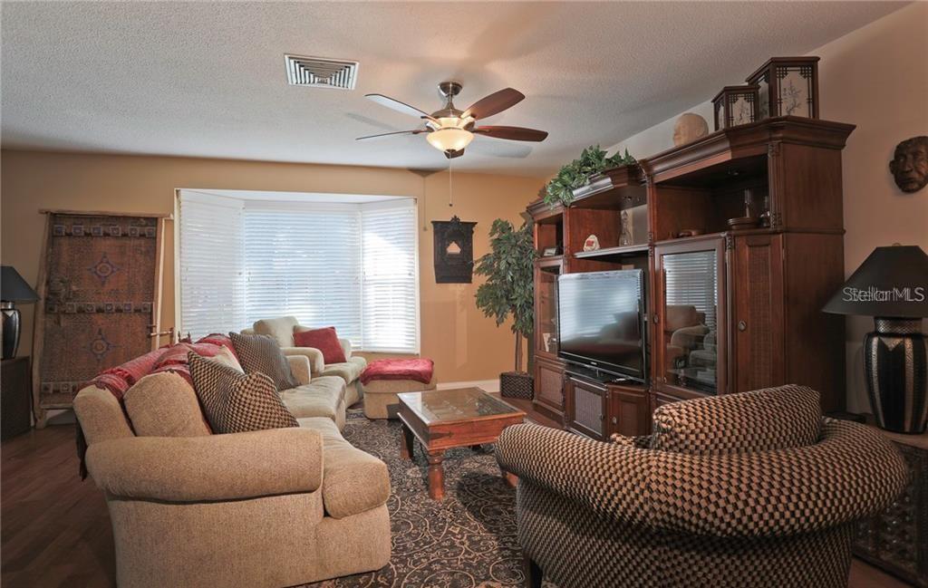 A living room features a large wooden entertainment center, a beige sofa, and a ceiling fan — 2929 MAYFLOWER STREET, SARASOTA, FL