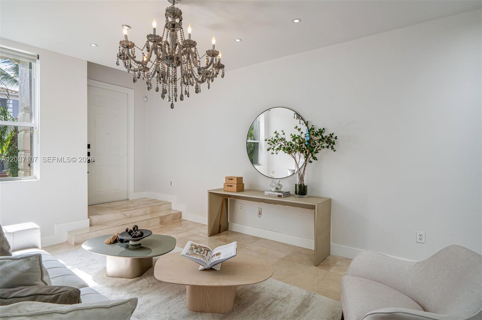 A bright living room features a crystal chandelier, a console table, and a round mirror — 21156 NE 33rd Ave, Aventura FL 33180, AVENTURA, FL