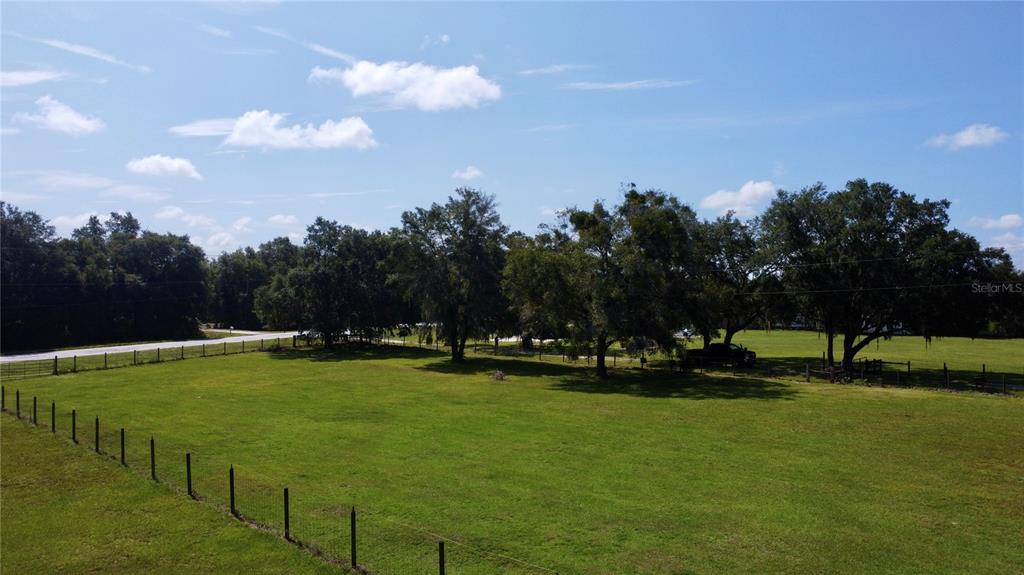 A wide, grassy field is bordered by a wire fence and a line of trees — OLD LAKELAND HIGHWAY, DADE CITY, FL