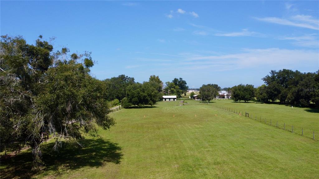 An aerial view of a large, grassy field bordered by trees and a wire fence — OLD LAKELAND HIGHWAY, DADE CITY, FL