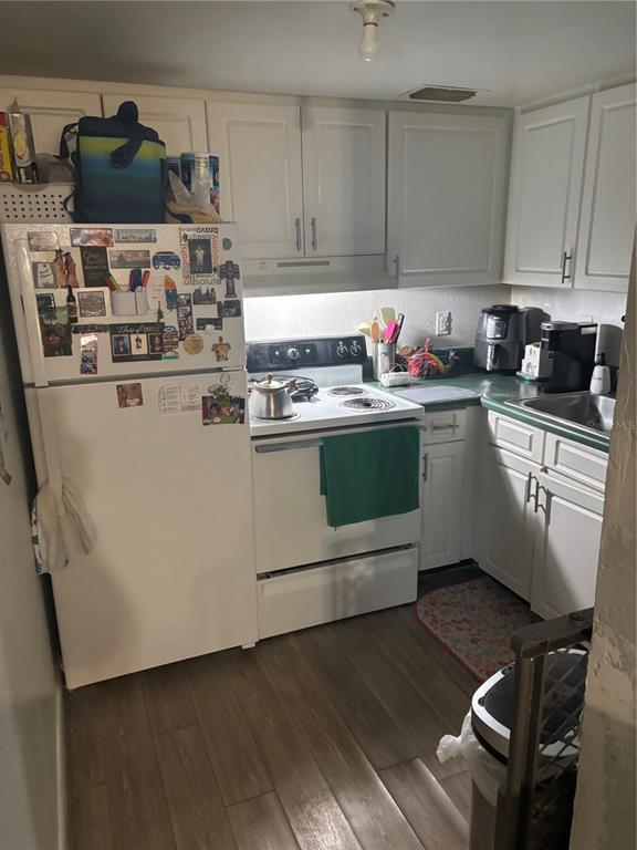 A small kitchen features white cabinets, a white refrigerator, a stove, and wood-look flooring — 732 MCDOUGALL COURT UNIT 732, ORLANDO, FL