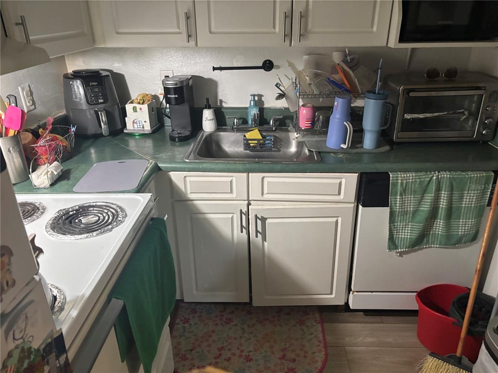 A kitchen features white cabinets, a green countertop, a stainless steel sink, and various appliances — 732 MCDOUGALL COURT UNIT 732, ORLANDO, FL
