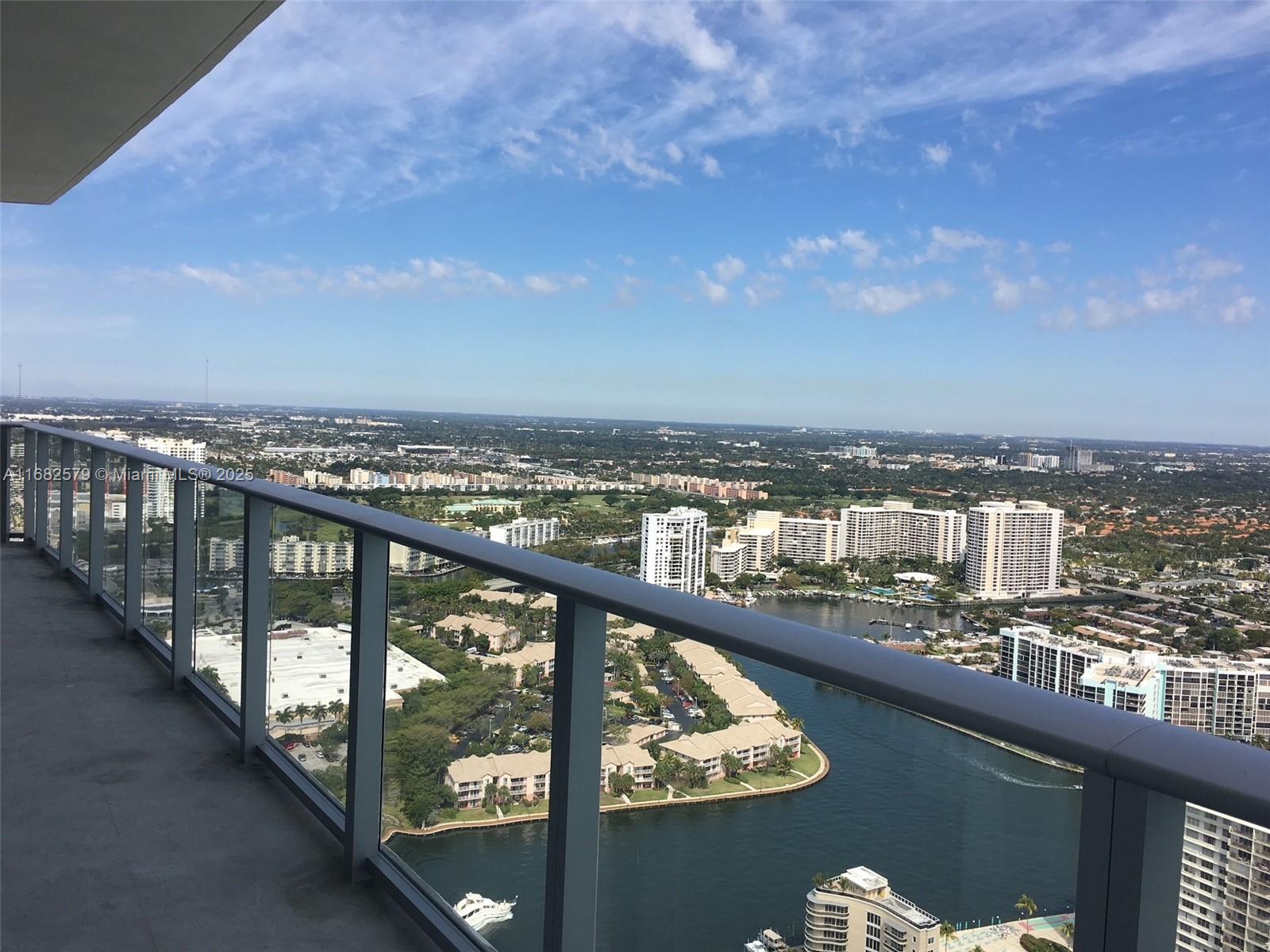 A high-rise balcony overlooks a waterway, residential buildings, and a sprawling suburban landscape — 4111 S Ocean Dr # 2712, Hollywood FL 33019, HOLLYWOOD, FL