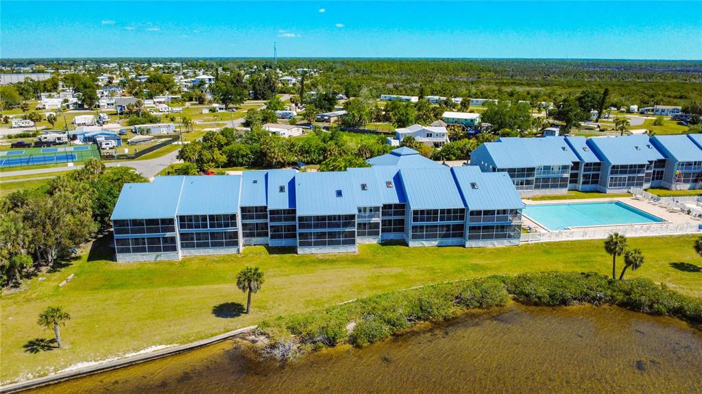 An aerial view shows a multi-story residential building with blue roofs next to a pool — 4410 WARREN AVENUE UNIT 101, PORT CHARLOTTE, FL