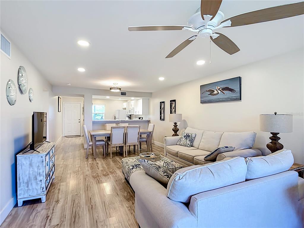 A living room and dining area with light wood floors, white furniture, and a ceiling fan — 4410 WARREN AVENUE UNIT 101, PORT CHARLOTTE, FL