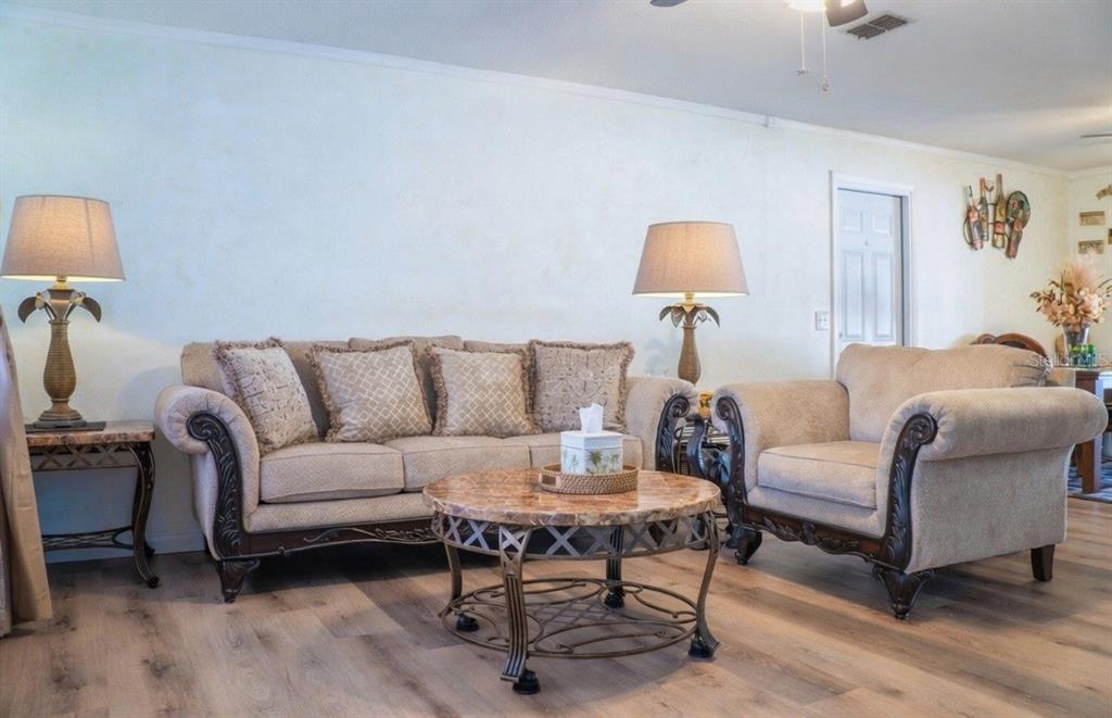 A living room features a beige sofa and armchair, a round marble coffee table, and lamps — 27197 SIMONA AVENUE, BROOKSVILLE, FL