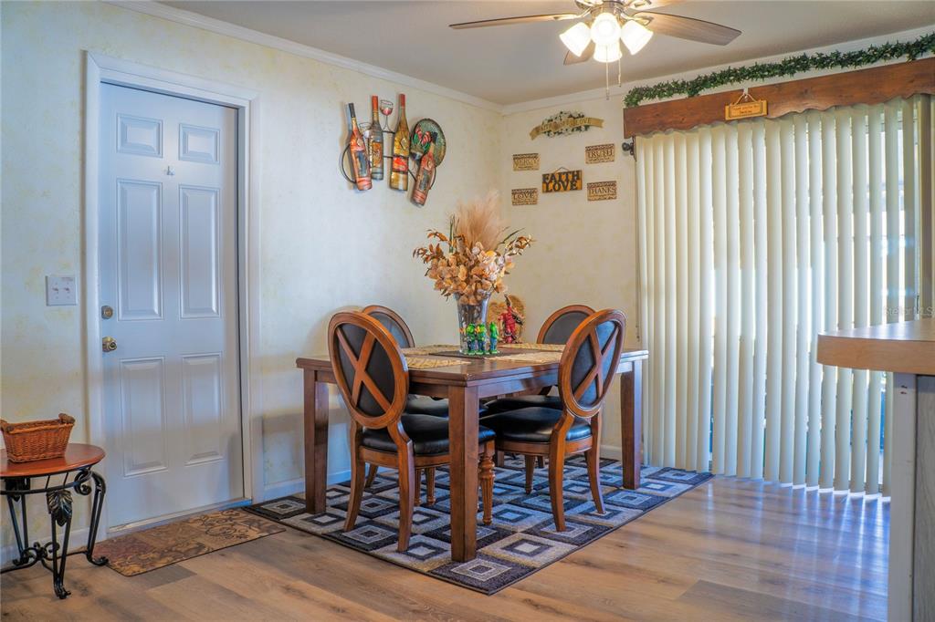 A dining room with a wooden table, four chairs, a rug, and vertical window blinds — 27197 SIMONA AVENUE, BROOKSVILLE, FL