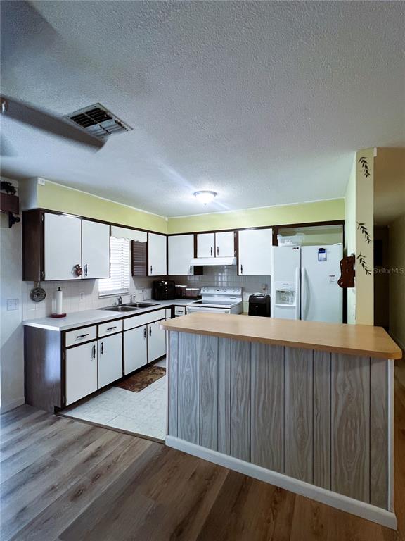 A kitchen features white cabinets, a wood-paneled breakfast bar, and light-colored flooring — 27197 SIMONA AVENUE, BROOKSVILLE, FL