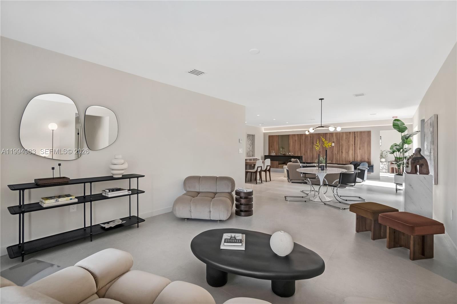 A modern, open-concept living and dining area features neutral tones, contemporary furniture, and wood paneling — 6207 SW 10th St, West Miami FL 33144, WEST MIAMI, FL