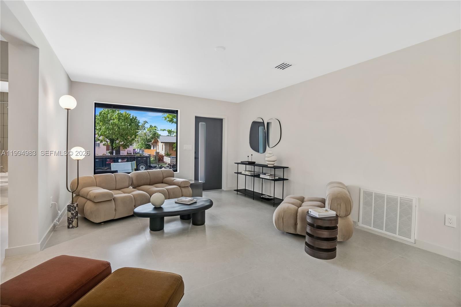 A modern living room features light tile floors, a tan sectional sofa, and a black console — 6207 SW 10th St, West Miami FL 33144, WEST MIAMI, FL