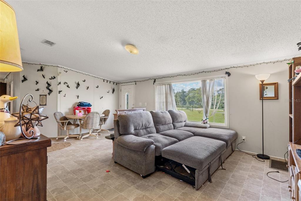 A living room with tile flooring, a gray sectional sofa, and a small dining area — 13317 MOON ROAD, BROOKSVILLE, FL